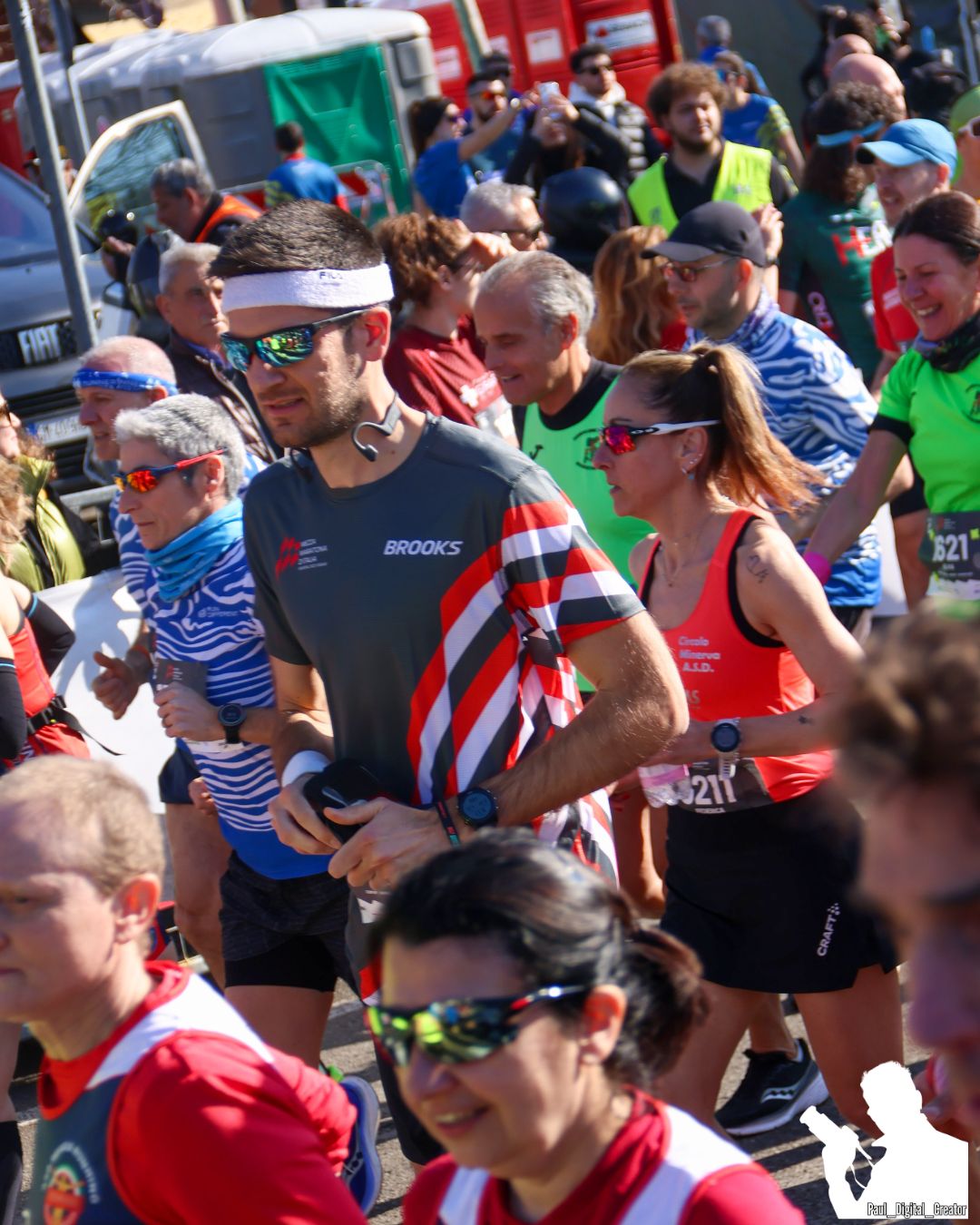 atleta che corre in primo piano con occhiali da sole colorati