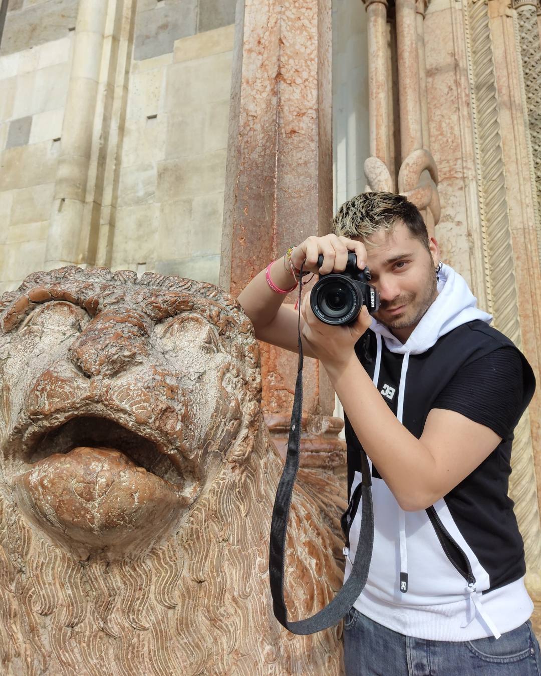 Paul con fotocamera in mano che guarda l'obiettivo con leone del duomo di Modena vicino