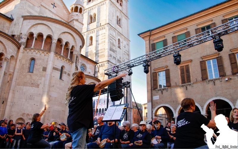 la dirigente d'orchestra con le mani in alto rivolta verso il gruppo