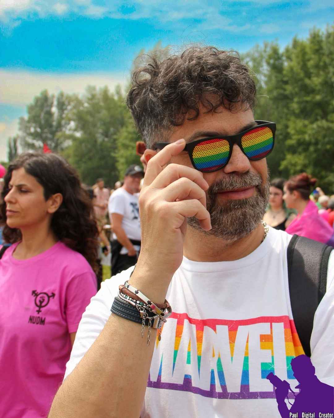 Un manifestante che indossa occhiali arcobaleno e maglia arcobaleno firmata Marvel