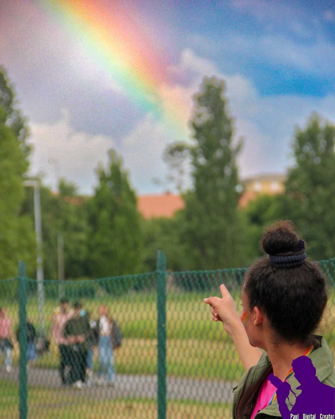Una ragazza di fronte al parco Ferrari voltata di spalle che indica un arcobaleno