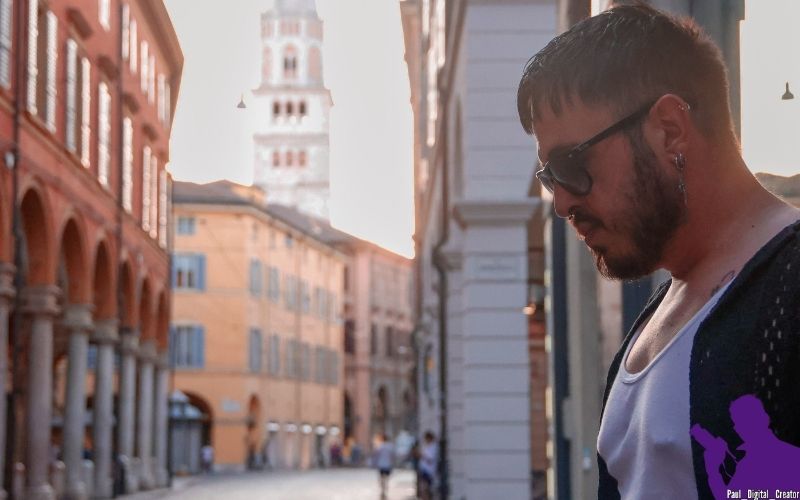 un modello che guarda in basso in via Emilia a Modena, indossa un paio di occhiali da sole