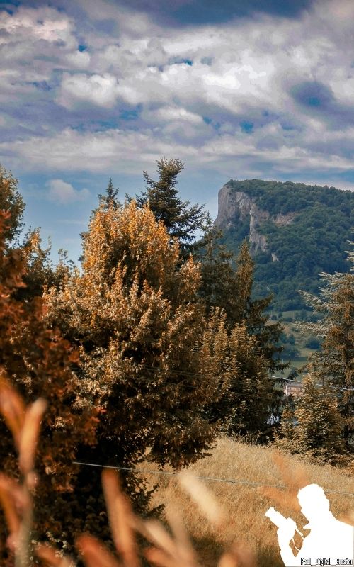 Pietra di Bismantova vista sul lato destro della foto con alberi dalle foglie arancioni e cielo azzurro